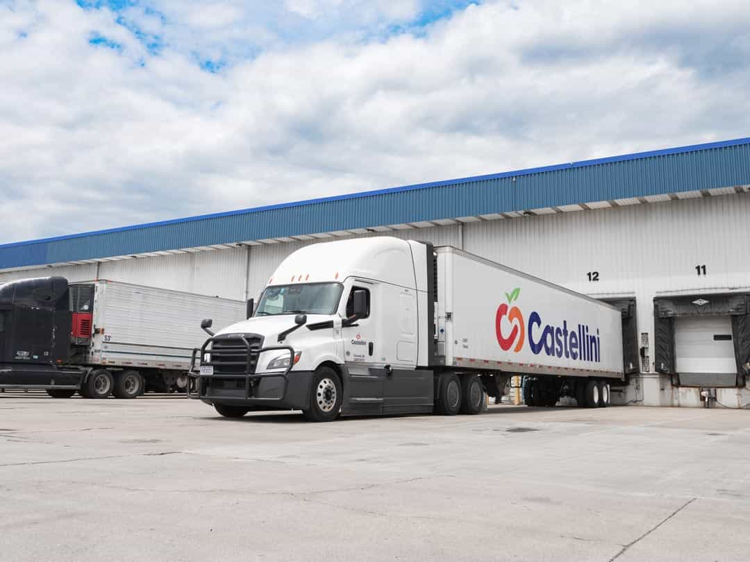 Castellini Company LTL distribution tractor trailer trucks with cold storage parked in a loading dock at building